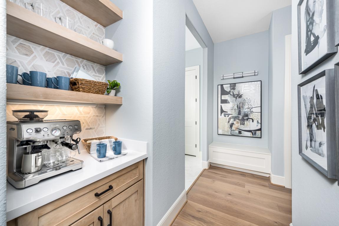 Coffee bar with espresso maker, blue painted walls and blue mugs on light wood shelves